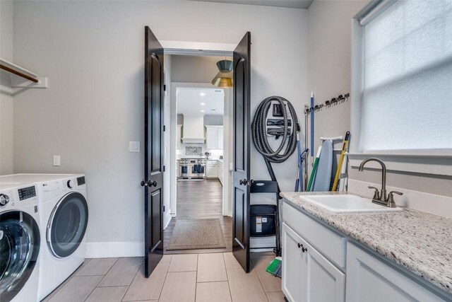 laundry area featuring cabinets, sink, light hardwood / wood-style flooring, and washer and dryer