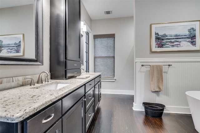 bathroom featuring a tub to relax in, hardwood / wood-style floors, and dual bowl vanity