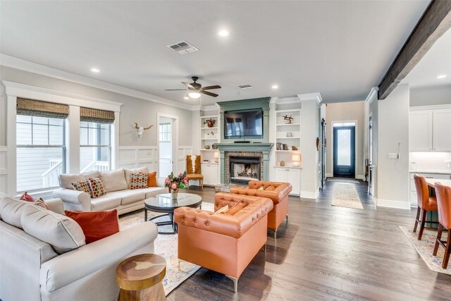 living room with ornamental molding, ceiling fan, wood-type flooring, and a healthy amount of sunlight