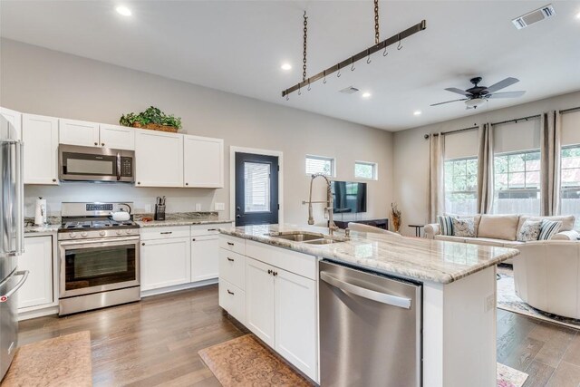 kitchen featuring white cabinetry, wood-type flooring, appliances with stainless steel finishes, and an island with sink