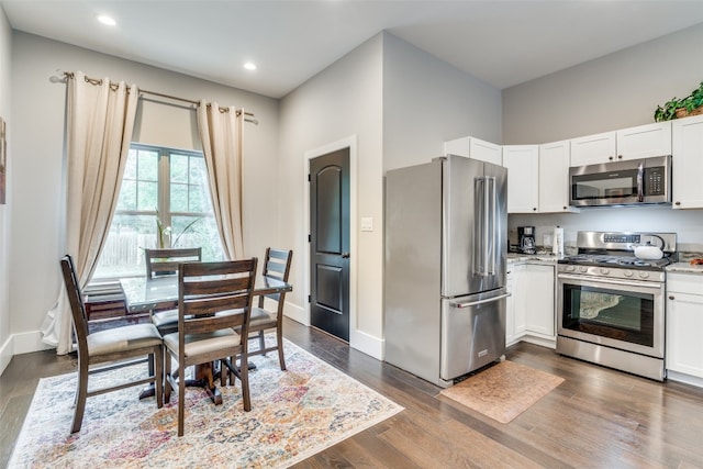 kitchen with appliances with stainless steel finishes, dark hardwood / wood-style flooring, and white cabinetry