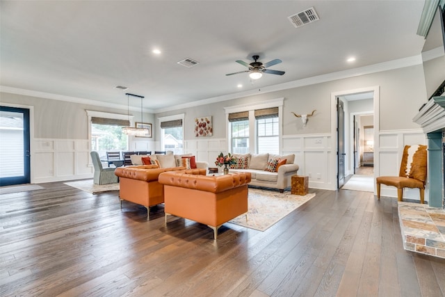 living room with dark wood-type flooring, ceiling fan, and ornamental molding