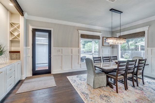 dining area with dark wood-type flooring, ornamental molding, and a notable chandelier