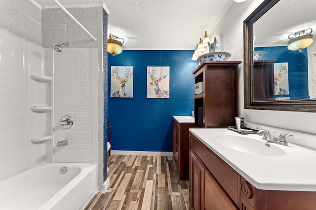 bathroom with crown molding, a textured ceiling, hardwood / wood-style flooring, vanity, and washtub / shower combination