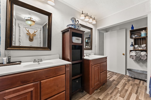 bathroom with hardwood / wood-style floors, a textured ceiling, vanity, and ornamental molding