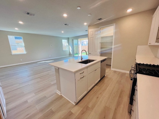 kitchen with a center island with sink, white cabinetry, light wood-type flooring, sink, and stainless steel dishwasher