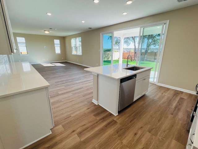 kitchen with sink, light hardwood / wood-style floors, white cabinets, dishwasher, and a kitchen island with sink