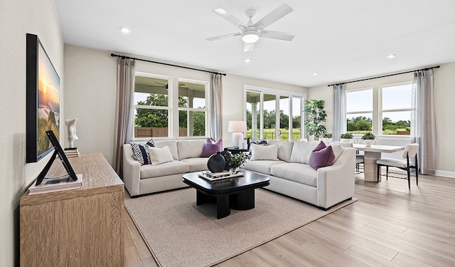 living room featuring light wood-type flooring, ceiling fan, and a healthy amount of sunlight