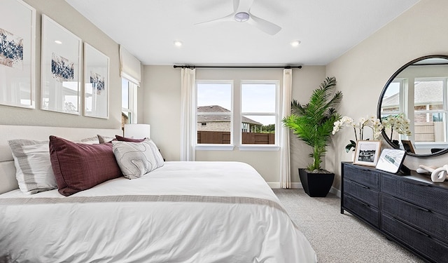 carpeted bedroom featuring multiple windows and ceiling fan