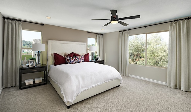 carpeted bedroom featuring multiple windows and ceiling fan