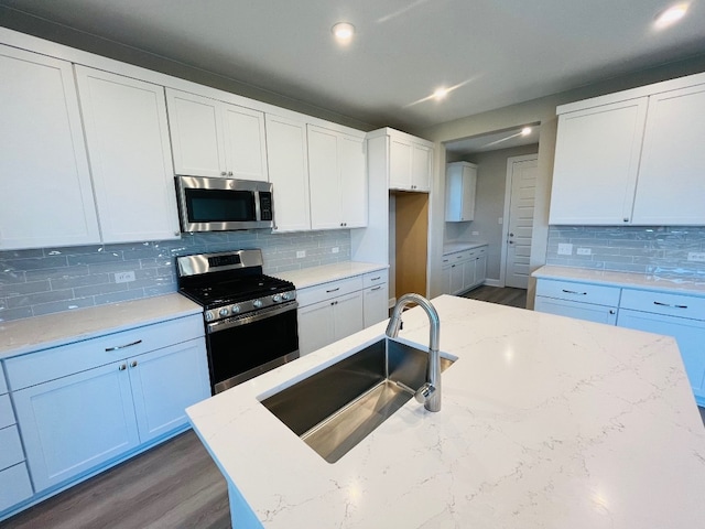 kitchen with white cabinetry, sink, light stone counters, appliances with stainless steel finishes, and dark hardwood / wood-style flooring