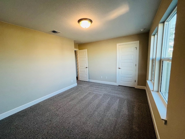 unfurnished bedroom featuring a textured ceiling, a closet, and dark carpet