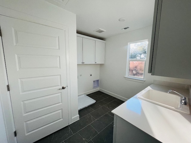 laundry area with cabinets, dark tile patterned floors, sink, and electric dryer hookup