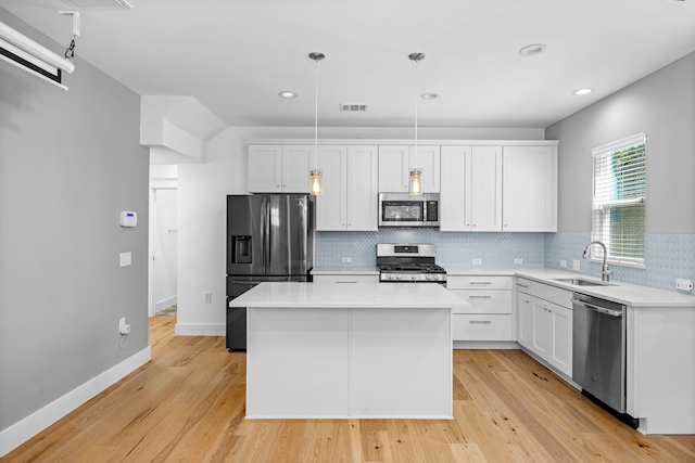 kitchen featuring stainless steel appliances, white cabinets, and hanging light fixtures