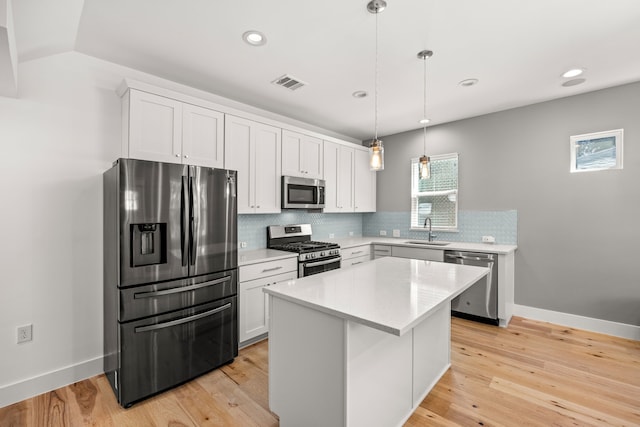 kitchen with sink, white cabinets, a center island, pendant lighting, and appliances with stainless steel finishes