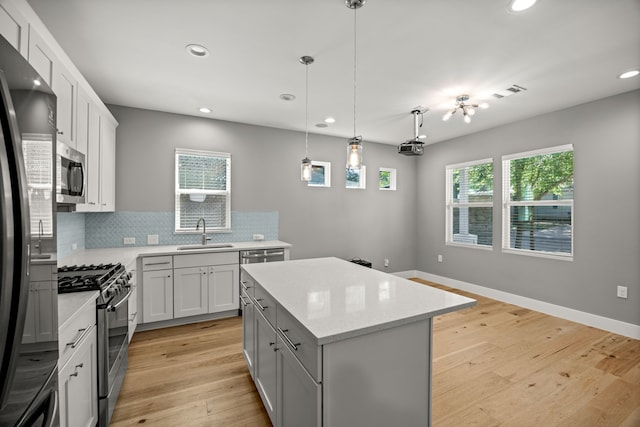 kitchen featuring a center island, light hardwood / wood-style floors, tasteful backsplash, appliances with stainless steel finishes, and sink