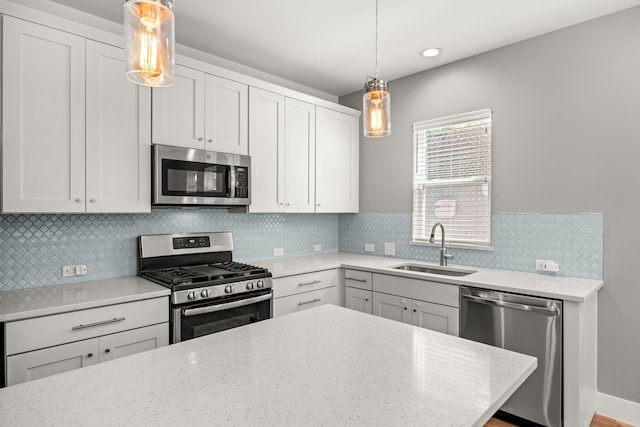 kitchen featuring sink, white cabinetry, pendant lighting, and appliances with stainless steel finishes