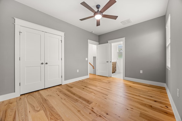 unfurnished bedroom featuring hardwood / wood-style flooring, ceiling fan, a closet, and ensuite bath