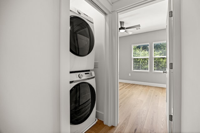 laundry room featuring stacked washer and dryer, ceiling fan, and light hardwood / wood-style floors