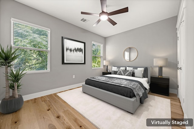 bedroom with hardwood / wood-style floors, ceiling fan, and multiple windows