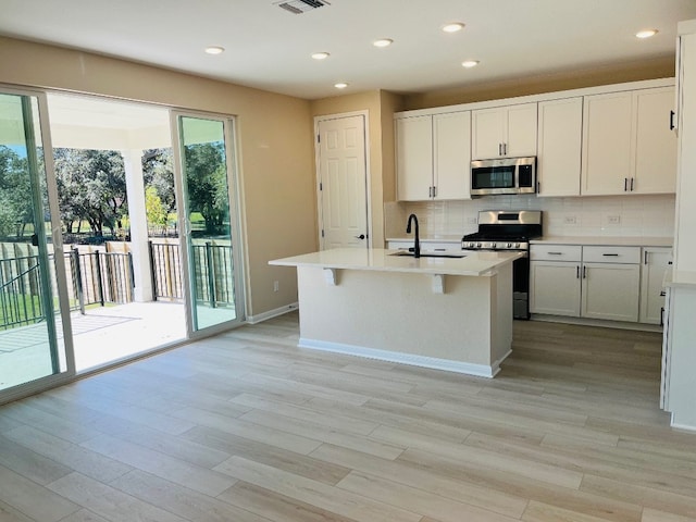 kitchen featuring a kitchen island with sink, stainless steel appliances, sink, and white cabinets