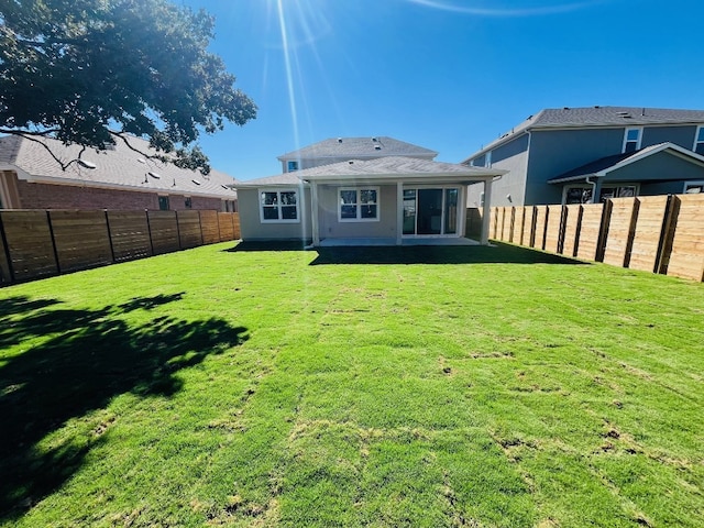 rear view of property featuring a yard and a patio area