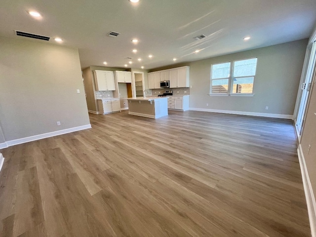 unfurnished living room featuring light hardwood / wood-style floors and sink