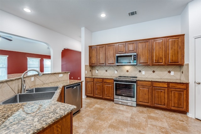 kitchen with light stone counters, stainless steel appliances, tasteful backsplash, and sink