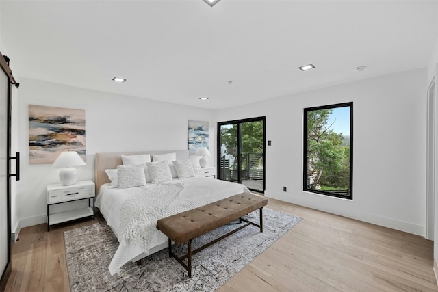 bedroom featuring a barn door, access to exterior, and light hardwood / wood-style floors