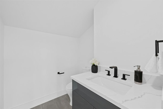 bathroom with lofted ceiling, vanity, hardwood / wood-style floors, and toilet