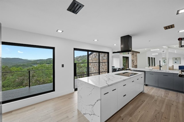 kitchen with a mountain view, light hardwood / wood-style floors, a kitchen island, and white cabinets