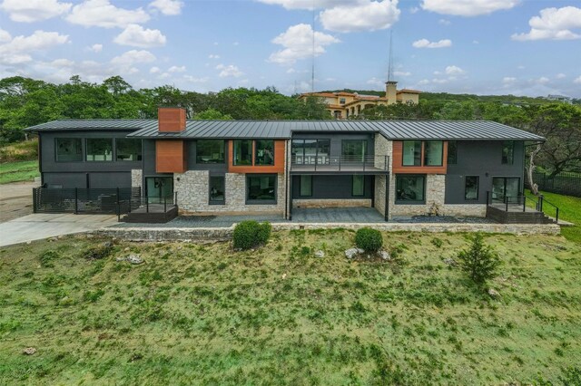 rear view of property with a lawn and a balcony