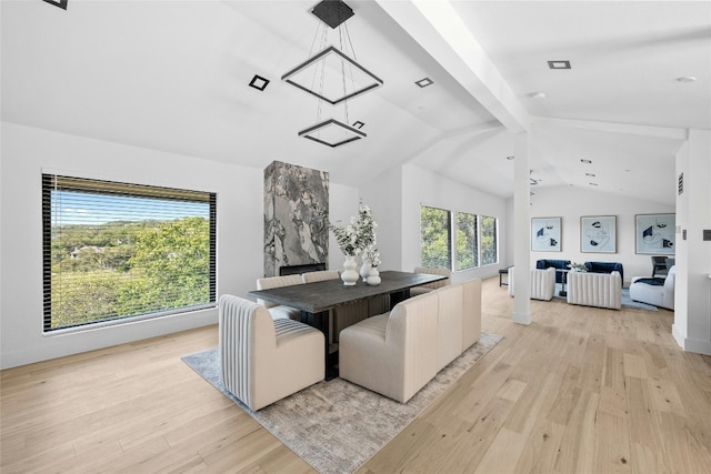 dining space featuring light hardwood / wood-style floors and vaulted ceiling with beams