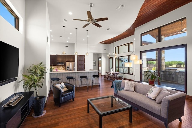 living room featuring ceiling fan, dark hardwood / wood-style floors, and a towering ceiling