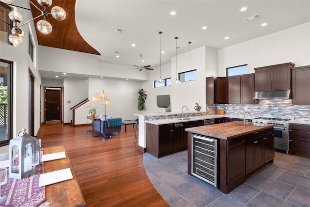 kitchen with pendant lighting, beverage cooler, sink, kitchen peninsula, and high end stove