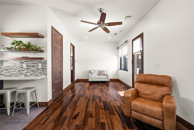 living area with dark wood-type flooring and ceiling fan