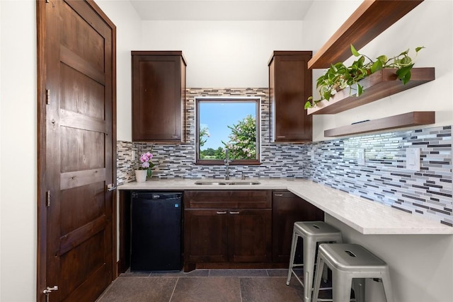 kitchen featuring sink, dark brown cabinets, black dishwasher, and decorative backsplash