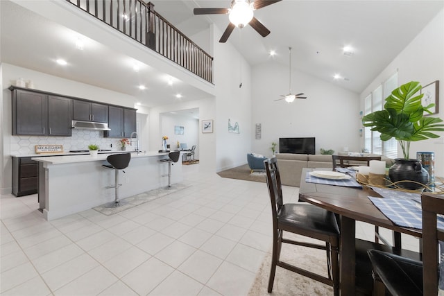 dining room with sink, high vaulted ceiling, ceiling fan, and light tile patterned floors