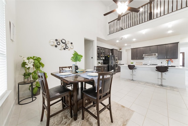 dining space with a high ceiling, ceiling fan, and light tile patterned floors