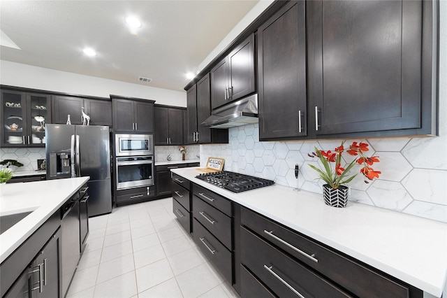 kitchen featuring stainless steel appliances, light tile patterned flooring, decorative backsplash, and dark brown cabinets