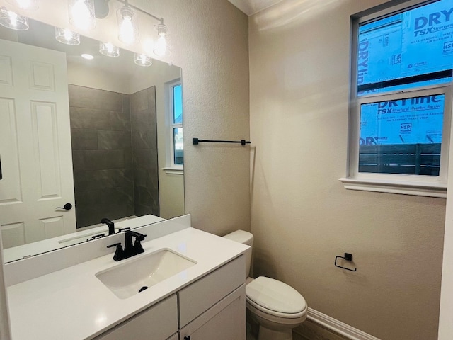 bathroom with tiled shower, vanity, and toilet