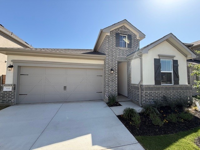 533 Raleigh Dr, Georgetown, TX 78633 - view of front of home featuring concrete driveway, brick siding, stucco siding, and a garage
