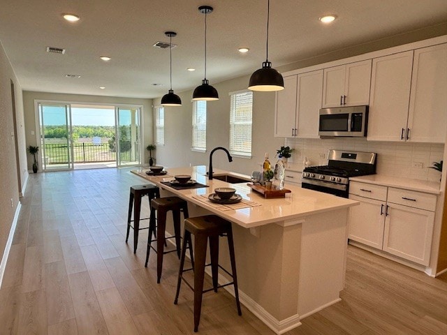 533 Raleigh Dr, Georgetown, TX 78633 - kitchen with stainless steel appliances, a sink, light wood-style floors, recessed lighting, and white cabinets