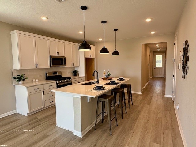 533 Raleigh Dr, Georgetown, TX 78633 - kitchen featuring appliances with stainless steel finishes, a sink, white cabinets, light wood-style flooring, and recessed lighting