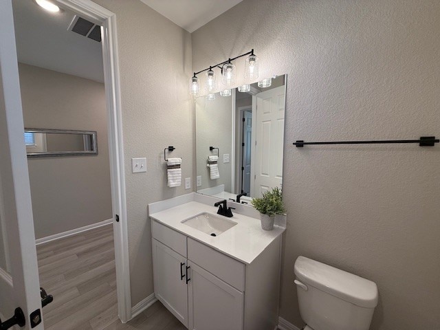 533 Raleigh Dr, Georgetown, TX 78633 - bathroom featuring vanity, toilet, wood finished floors, and a textured wall