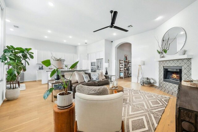 living room with light wood-type flooring, a fireplace, and ceiling fan