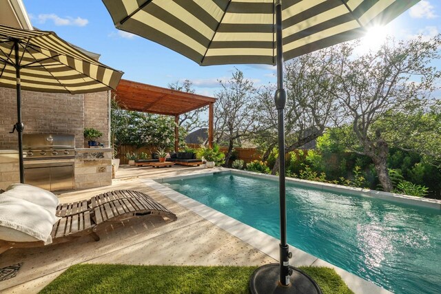 view of swimming pool with an outdoor kitchen, a grill, and a patio area