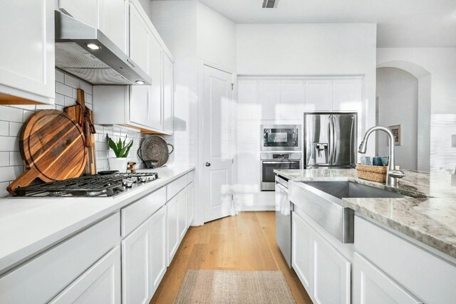 kitchen with white cabinets, stainless steel appliances, and exhaust hood