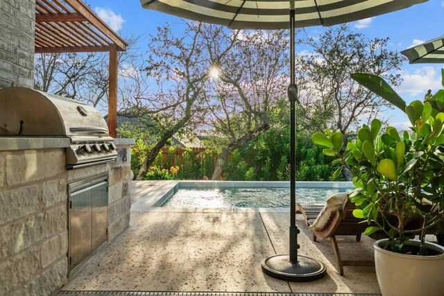 view of pool with an outdoor kitchen, area for grilling, and a patio