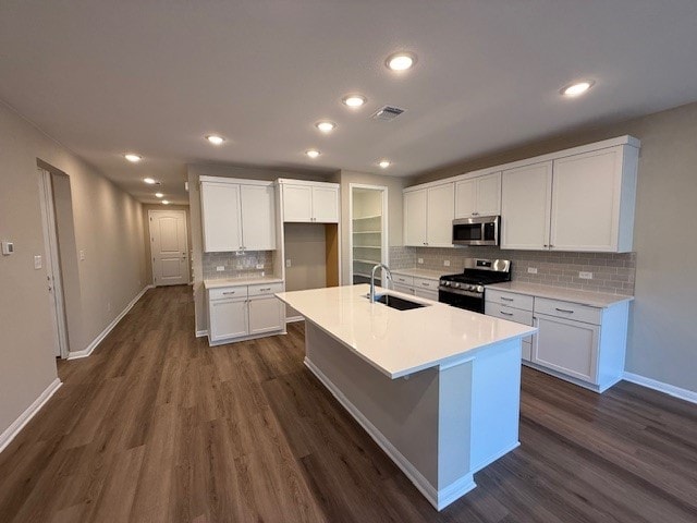 kitchen with sink, dark hardwood / wood-style flooring, a kitchen island with sink, white cabinets, and appliances with stainless steel finishes